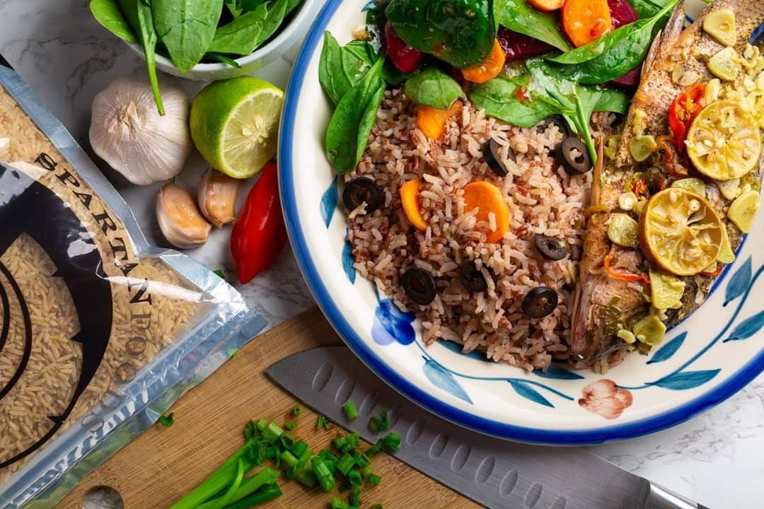 Prepared Caribbean meal plated beside branded packaged rice